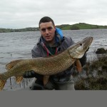 Boatman Justin Bird holds the 26 lb. pike for captor Jim 'Red' McKeever and is the Catch of the Week.