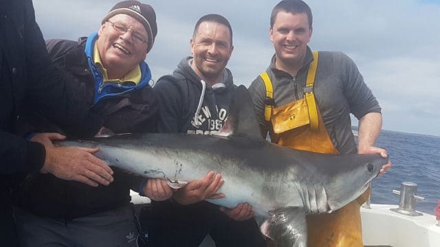 Some of the crew aboard the Brazen Hussy II with the boat's first porbeagle shark, and skipper John Fleming on the right.