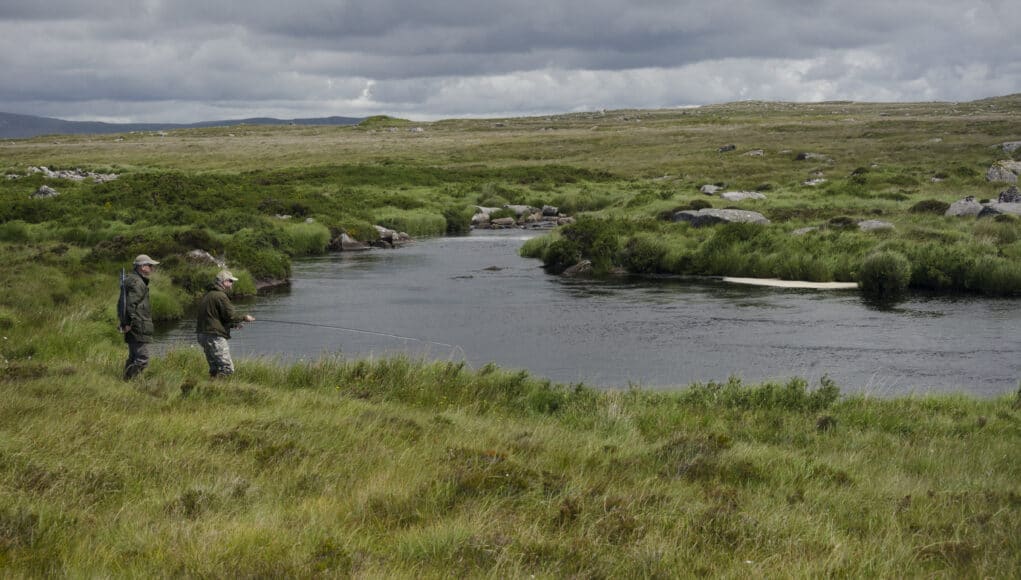 Anglers on river set in wild bogland scenery with mountains in far distance