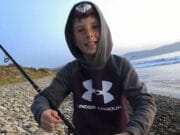 Bass Time in Kerry Young angler on beach holding a bass